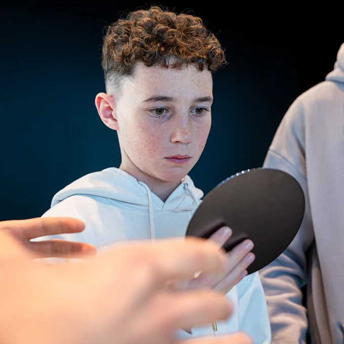 A young boy looking at and holding a wafer.\n