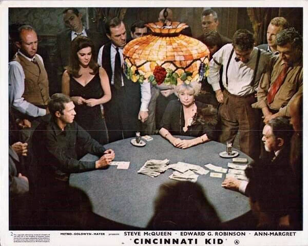 Still photo from THE CINCINNATI KID with Steve McQueen, Joan Blondell, and Edward G. Robinson  sitting at a poker table, with a bunch of people watching them play