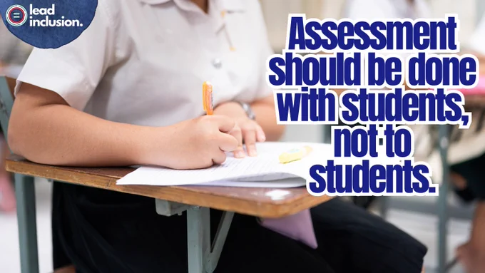 A student writes in a notebook at a classroom desk. The text reads, "Assessment should be done with students, not to students." 
