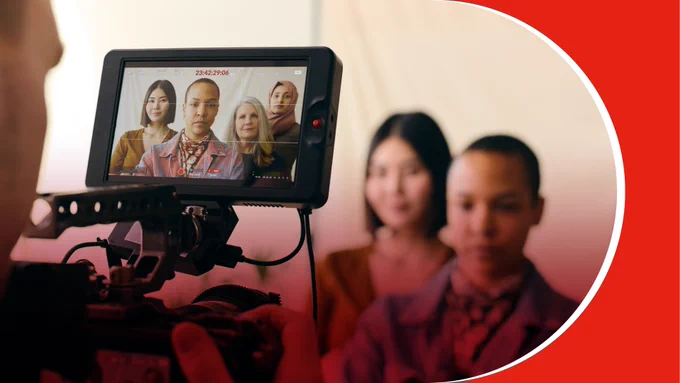 Camera monitor displaying a group of four diverse people posing for a video shoot indoors.