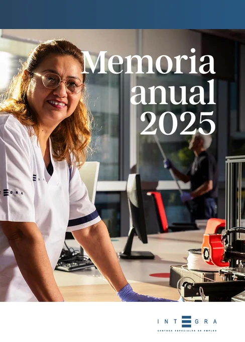 Portada de la Memoria Anual 2025. Una trabajadora de Integra CEE aparece en primer plano con uniforme de limpieza corporativo. Se encuentra en un entorno de oficinas, con mesas, ordenadores y una impresora 3D. Al fondo y desenfocado, otro compañero realiza labores de limpieza de cristales en unos grandes ventanales. 
