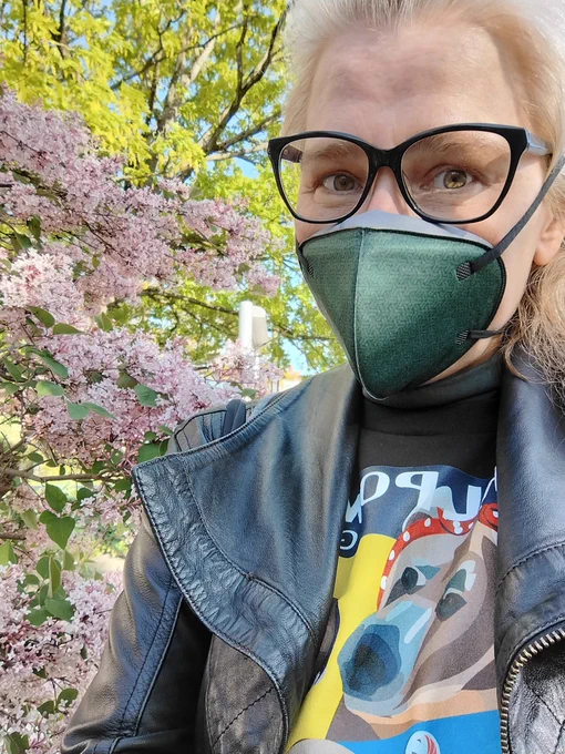 Woman wearing a green Rackmask pink flowers in the background 