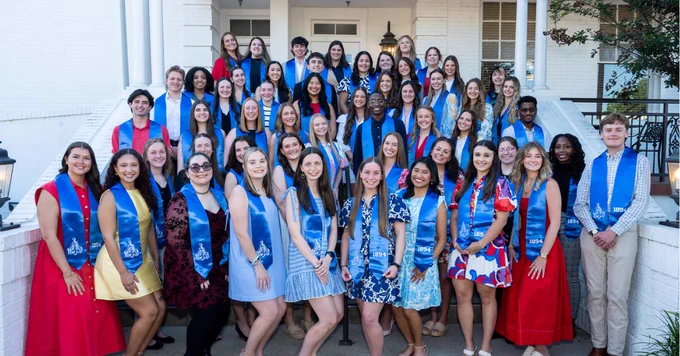 A group stands with blue graduation stoles signifying their completion of the 1894 Leadership Series