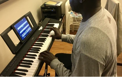A person playing a digital piano with a tablet displaying a keyboard app.