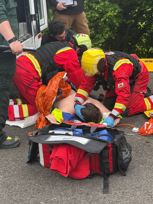 People in PPE working on a patient who is injured with supplies around them