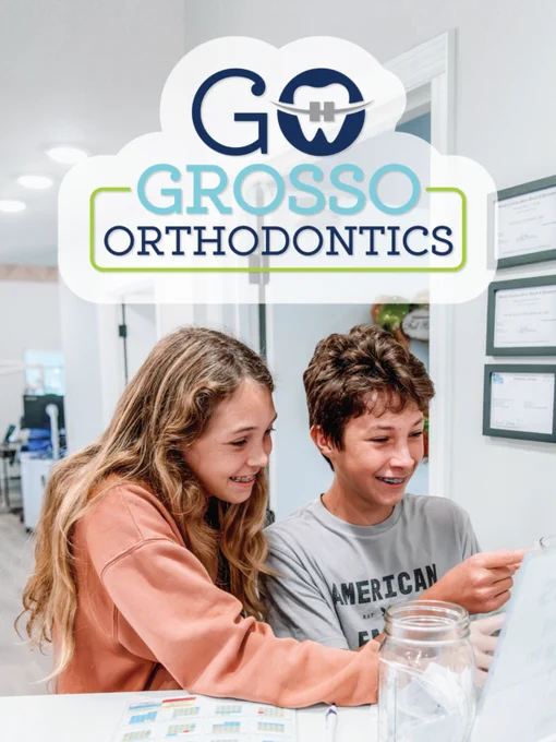 Two young people smiling and checking a chart at an orthodontic clinic. The atmosphere is cheerful and welcoming.