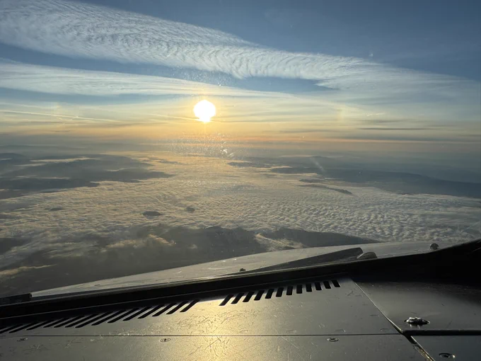 View out of the front window into the rising sun over a partially cloudy Portugal.