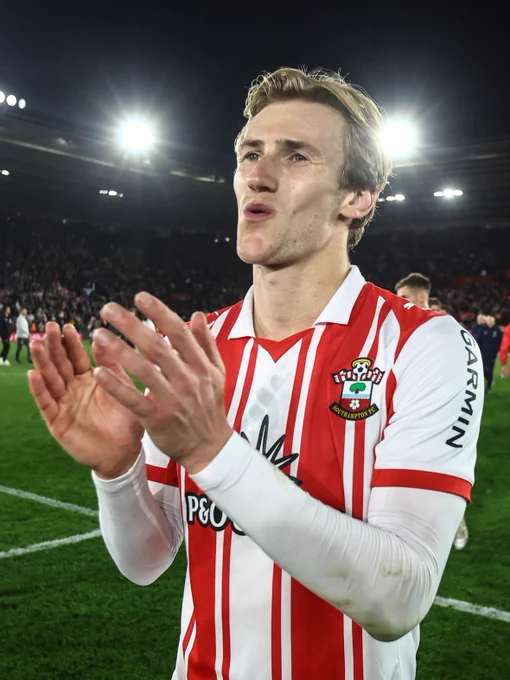 An image of Flynn Downes applauding the Southampton fans following the semi-final win over Middlesbrough, wearing the red and white striped home shirt.