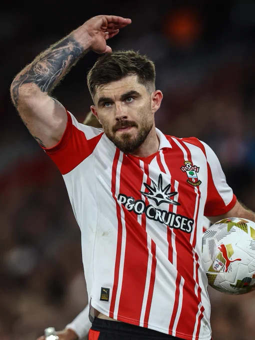 Ryan Manning raises one arm in the air wearing the red and white striped home shirt.