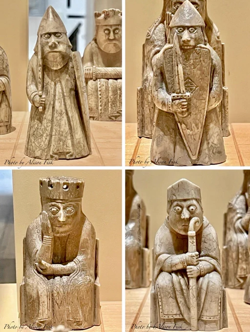 My photo shows four carved chess pieces, creamy beige in colour against a warm beige display surface at the National Museum of Scotland. Dated c. 1150-1200

Top L - warder piece, standing, wearing a long garment and conical helmet. He holds a drawn sword in his right hand, in his left, a long, kite-shaped shield. Carved from sperm whale tooth. H 9.3 cm x W 4.3 cm

Top R- warder piece, also known as a ‘berserker’. Standing, wearing a long garment and conical helmet. He holds a drawn sword in his right hand in front of a large kite-shaped shield. He has large eyes and bites the top of his shield. Carved from Walrus Ivory. H 8.2 cm x W 3.9 cm

Bottom L - Queen piece seated on a throne, cradling her face in her right hand. She wears a crown and a long dresss and cloak. Walrus ivory.  H 9.5 cm x W 5.1 cm

Bottom R - Bishop piece seated on a throne with a staff known as a crozier held with both hands. He wears a long garment and cloak with decorative edging. Walrus  ivory. H 7.5 cm x W 4 cm