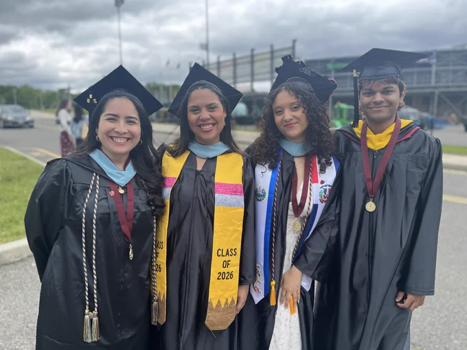 4 students smiling before ceremony began wearing regalia

