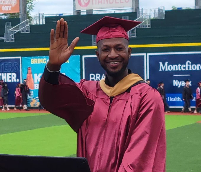 one student smiling and waving while processing