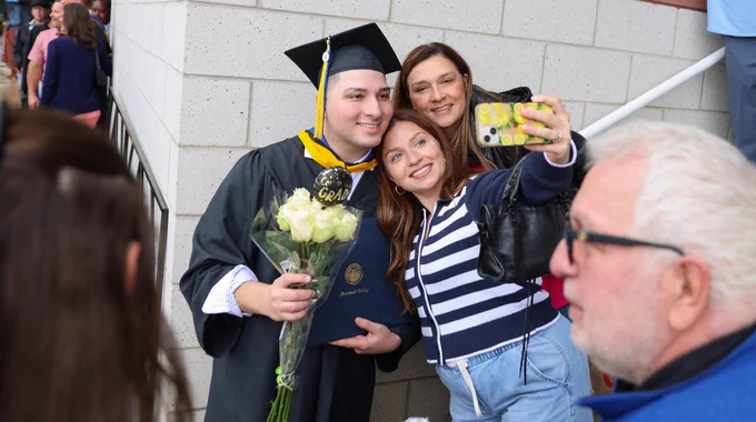 Three people pose for a selfie at Commencement. 