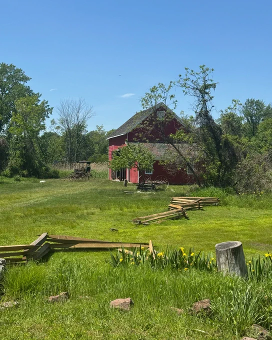 An old red barn with a horse-drawn carriage parked outside