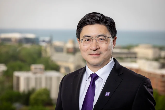 Mung Chiang wears a purple tie and a Northwestern \"N\" pin. The Evanston campus and Lake Michigan are visible in the background.