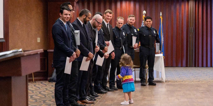 A child stands in front of a line of people in uniform.