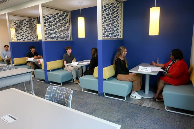 People engaged in one-on-one conversations during mock interviews for the Business Communication class.