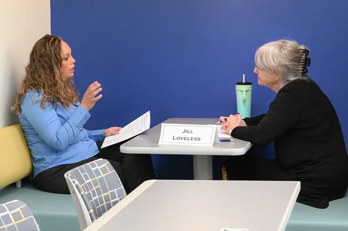 Two women engaged in a focused conversation across a small table.