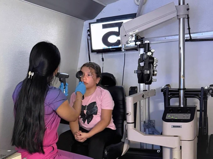 A photo of a child receiving an eye exam in the Miami Lighthouse Florida Heiken Mobile Eye Care Unit.