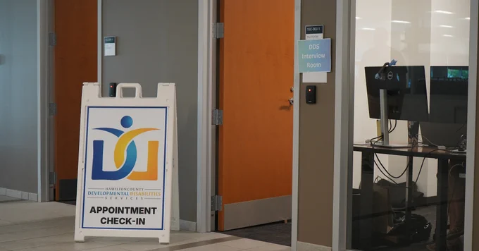A sign in a hallway reads "Hamilton County Developmental Disabilities Services Appointment Check-In" with a logo above the text.