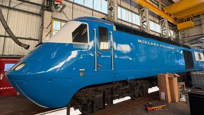 A Blue Pullman train is inside a maintenance shed. 
