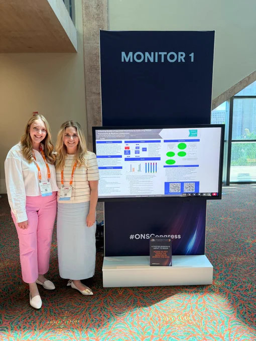 Kaylee Cooper and Lindsay Chorney standing next to one of their posters.