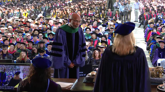 Emery Brown in academic regalia stands facing the dais as his citation is read in front of a massive crowd at Yale's commencement.