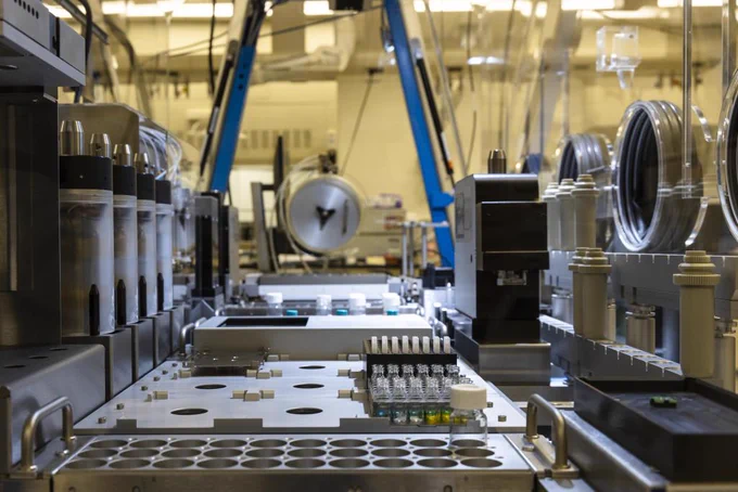 A laboratory with a set of tools controlled by robotics. There is a sample table with some test tubes in it.