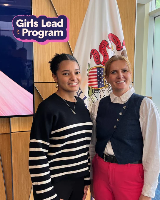Payton and Ula smile for a photo in front of the Illinois flag.