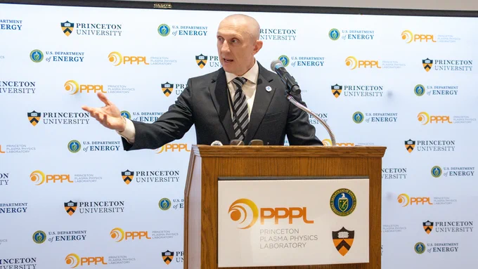 A person is speaking at a podium with a Princeton Plasma Physics Laboratory sign. The background features logos of Princeton University and the U.S. Department of Energy.