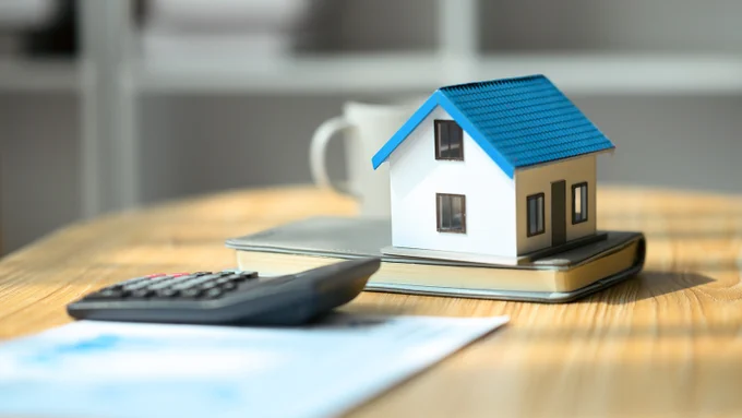 A miniature house sitting on top of a book on a desk.