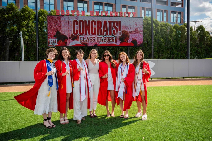 Photo of multiple BU women's soccer graduates posing with head coach Megan Burke (center)