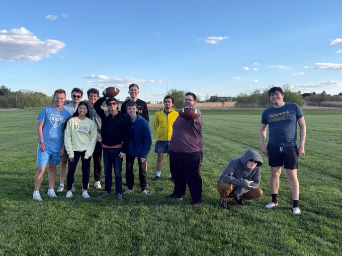 Students standing together, posing and holding footballs.