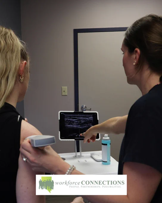 2 women in an exam room with medical tech. workforce connections logo