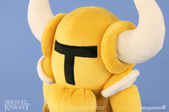 A closeup photo of the Gold Shovel Knight plush, showing its horns, epaulettes, and embroidered face details. 