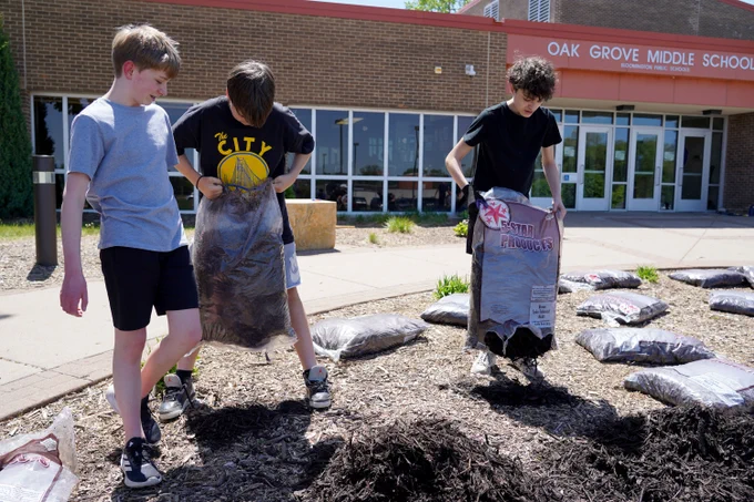 middle school students laying new mulch in the garden outside Oak Grove Middle School