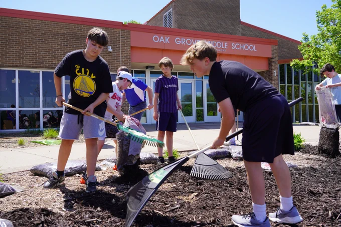 middle school students laying new mulch in the garden outside Oak Grove Middle School