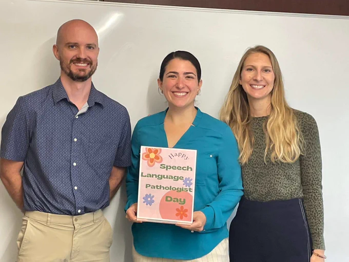 Group photo of 3 of Fixel's speech language pathologists holding a sign that reads "speech language pathologist day"