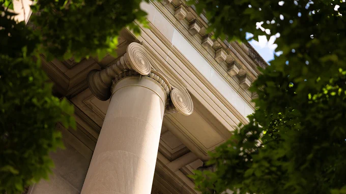Detail of a column outside Pound Hall, surrounded by the greenery of trees. (Liz McCue/University Communication and Marketing)
