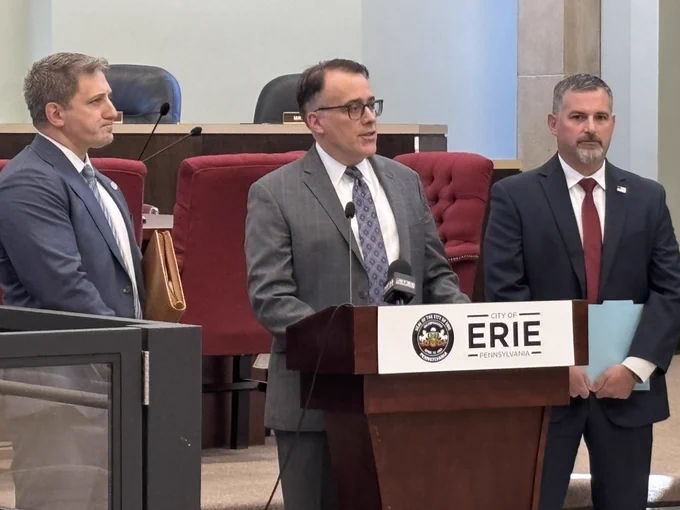 Image of three men behind and around podium