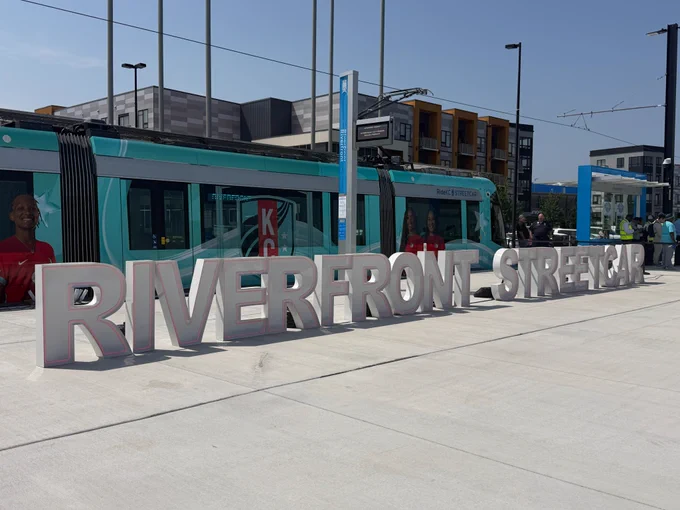 Streetcar at the riverfront stop, with large letters on the sidewalk spelling out "RIVERFRONT STREETCAR."