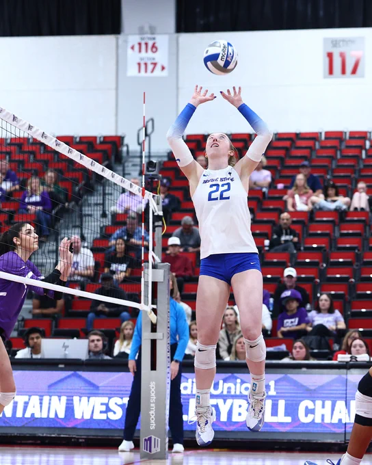 Boise State women's volleyball player Elle Cotton playing during a volleyball court jumping up to set a ball. 
