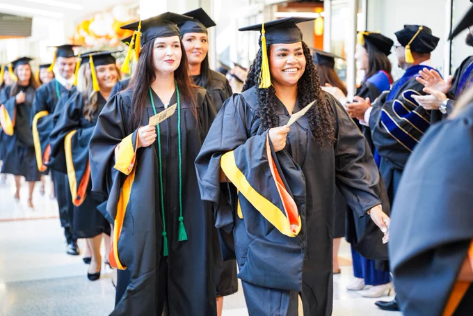 Graduates in cap and gown walking into ceremony