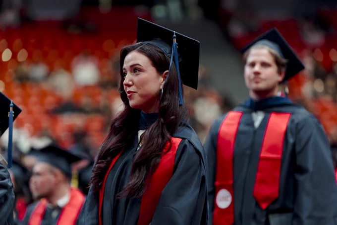 UIC grad stands in graduation regalia