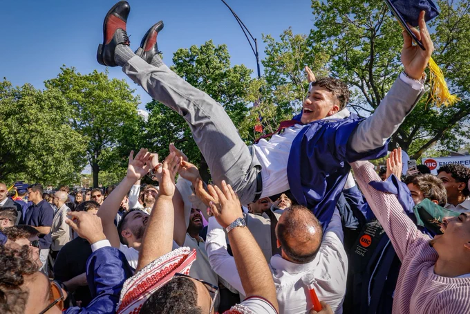 UIC grad is thrown into the air in celebration by family and friends