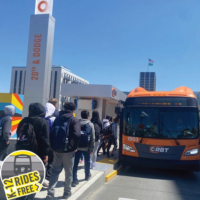 Photo of students boarding an ORBT bus at 20th Street and Dodge Street in Omaha, Nebraska. Logo in bottom left reads, "K-12 rides free".