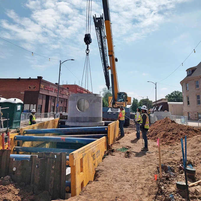 A construction crew lowers a manhole structure as part of underground storm and water upgrades in the City of Loveland, CO.