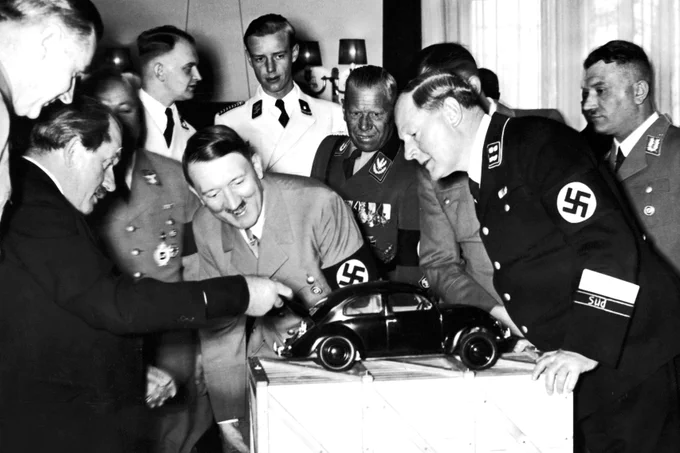 The Fuhrer admires a model of the Volkswagen with designer Ferdinand Porsche, left, and various Nazi officials in 1938. Industrialists such as Porsche and Krupp began paying from the German employer's association into the Hitler Fund on June 1, 1933. Over $3B in todays dollars were raised by 1945. 