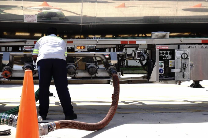 Image of a tanker truck driver hooking up a hose to the truck.