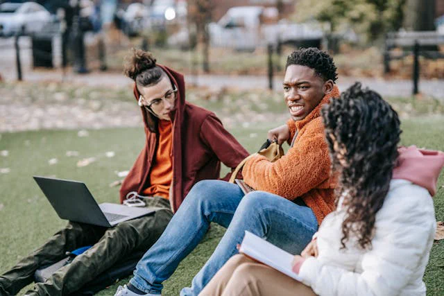 Group of diverse students studying together on a sunny day in the park.